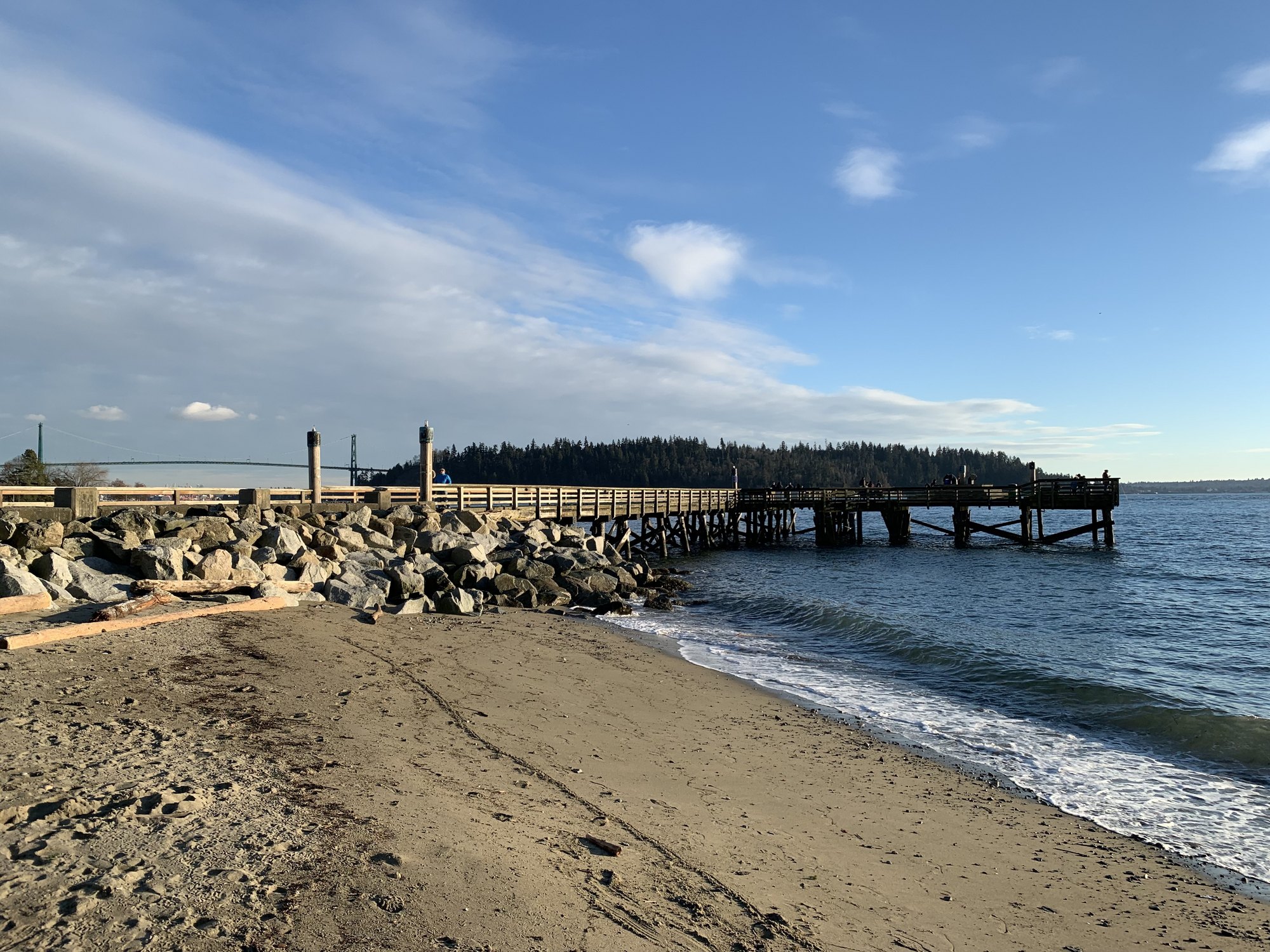 Ambleside pier and beach in West Vancouver, a short walk from Kouros Pezesh's office on Marine Drive, with the Lions Gate Bridge in the distance